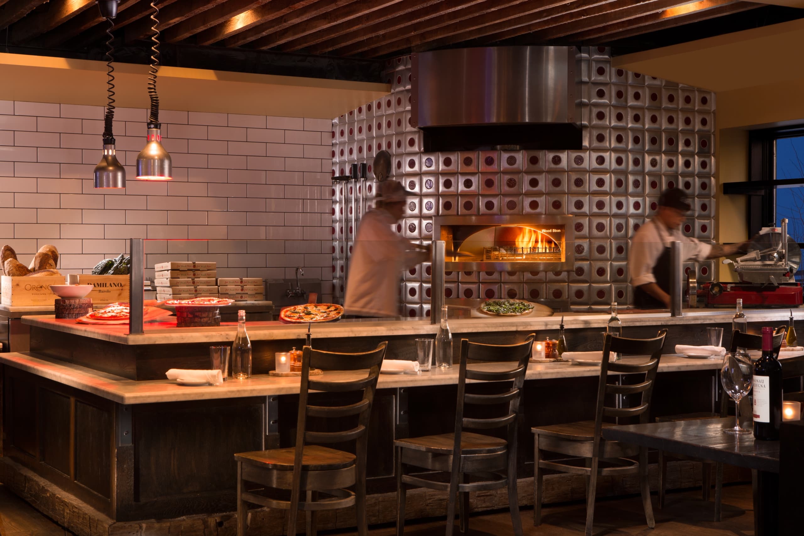 chef putting pizza in wood fire oven at Villagio Osteria