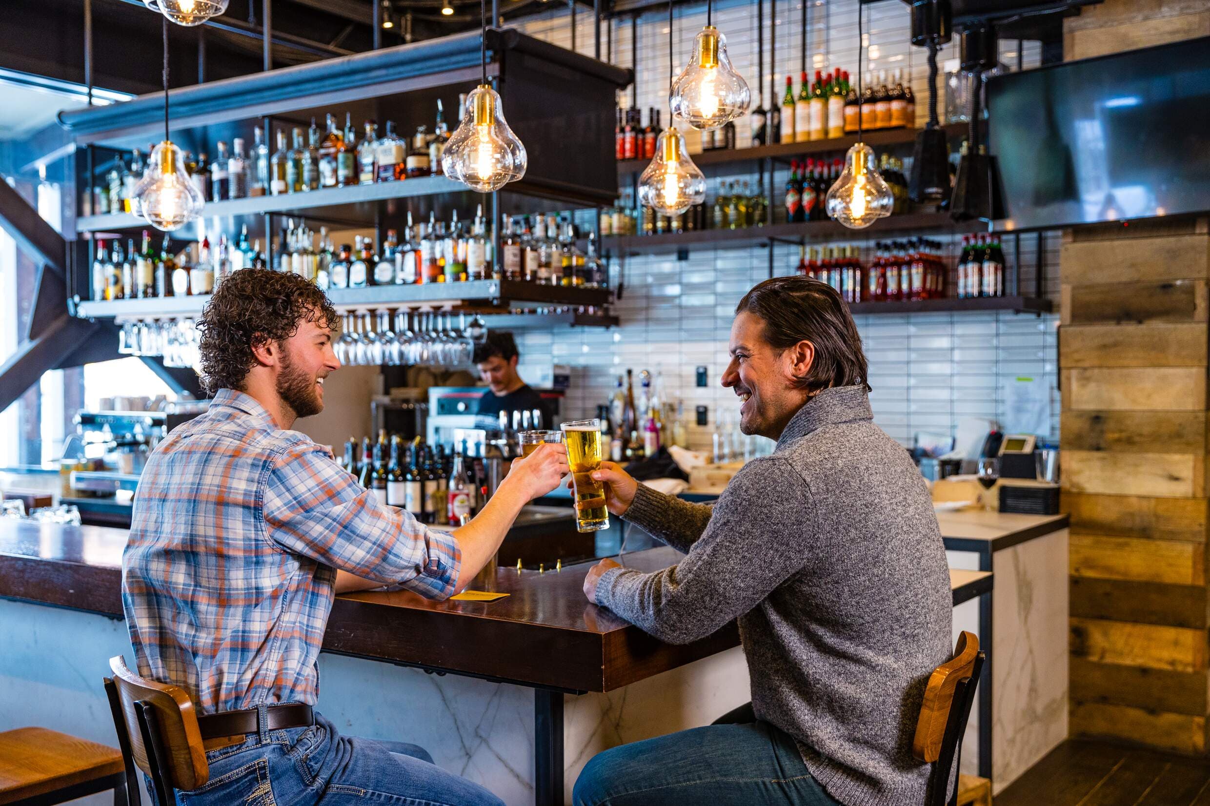 Two men cheers at the bar of Osteria Next Door.