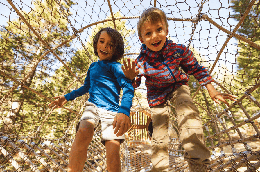 Two youth running and smiling through attraction at Jackson Hole kids Grand Adventure Camp located in Teton Village, Wyoming.