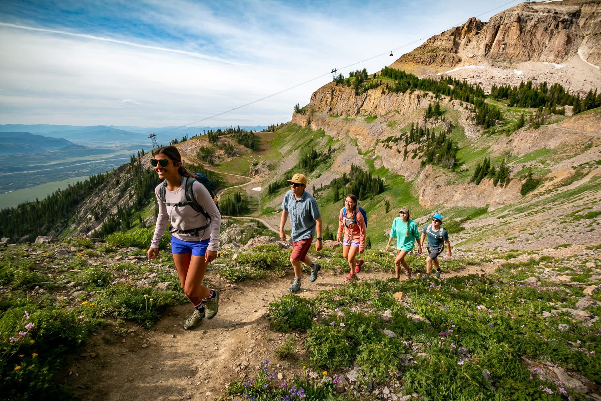 A group of four smiling and hiking up a mountain in Jackson Hole