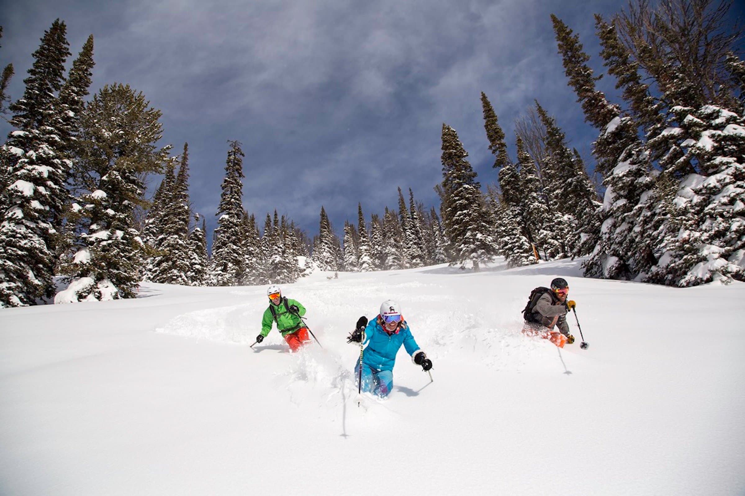 A trio heading down in the mountain during a Powder Skiing experience at Jackson Hole Mountain Resort
