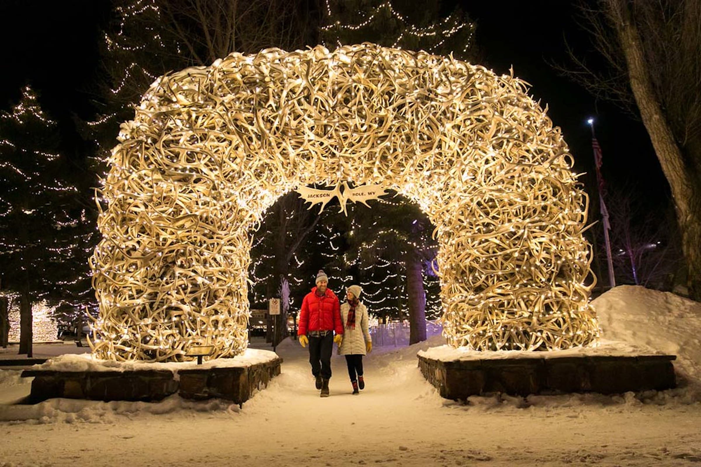 A couple walks through the Town of Jackson Winter Antler Arch