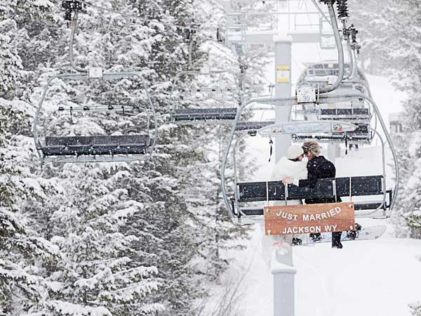Bride and groom on a ski lift with a just married sign.