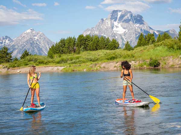 Two girls stand up paddleboarding.