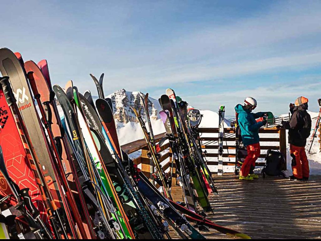 Skis lined up on a deck rail.