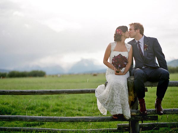 Bride And Groom Sitting On A Fence.